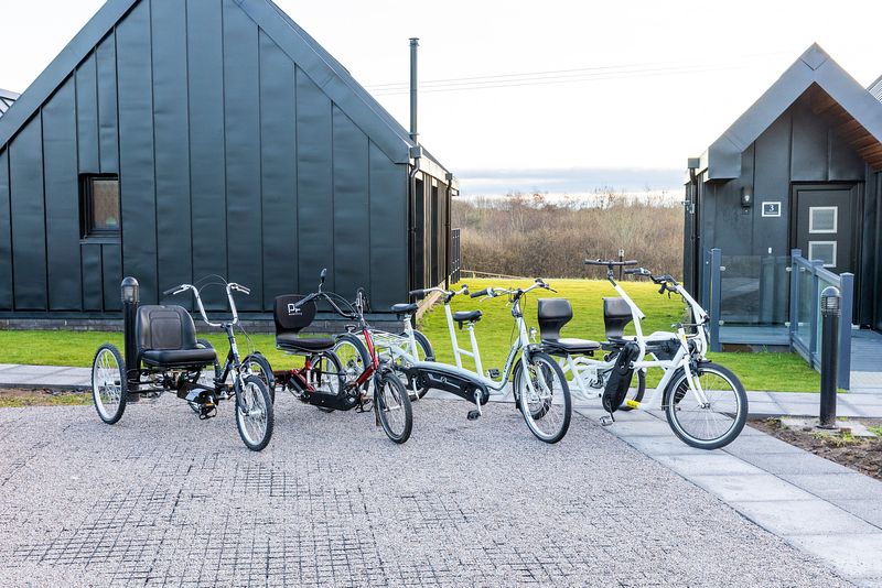 A selection of different bikes sit outside the rear of the chalets. There are tandem bikes with two seats, and bikes with large, comfortable looking seats.